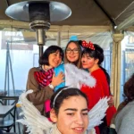 Tra maschere e sorrisi al Carnevale 2026 di ELO Epilessia Lombardia ETS: una ragazza vestita da angelo in primo piano, dietro di lei Minnie, un costume da unicorno e una donna con un grande fiocco al collo
