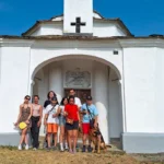 Foto di gruppo davanti alla cappella durante una passeggiata – vacanze estive ELO 2026