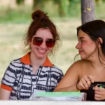 Due amiche in chiacchiere al tavolo all'aperto – vacanze ELO 2026 a Cantalupa